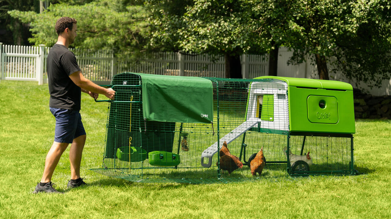 man moving the eglu cube portable plastic chicken coop