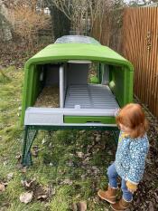 A child stood beside the green Eglu Cube chicken coop.