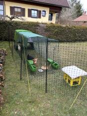 Green Eglu Cube setup in a back garden, with 3m run and extreme weather protection run cover attached