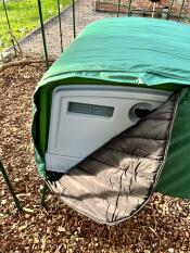 Close up of green, half zipped Extreme Temperature Jacket covering Eglu Cube Chicken Coop.