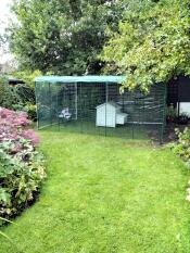 A large walk in chicken run set up in a garden.