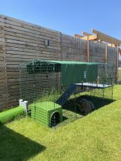 Green plastic Zippi Shelter inside a Zippi Rabbit Run with Zippi Tunnel attached in garden.