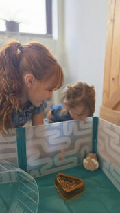 Two children admiring their hamster who is inside of the Omlet hamster playpen.