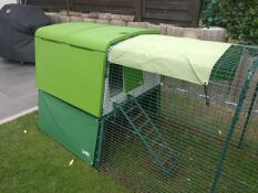 covers around a large green chicken coop with a run attached