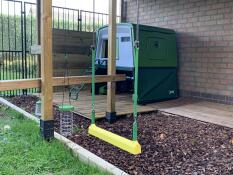 chicken swing outside a cube chicken coop in a garden with lots of omlet products