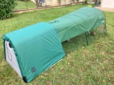 A guinea pig hutch covered with a green extreme temperatures blanket