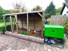 The green Eglu Cube chicken coop linked to a wooden walk in run.