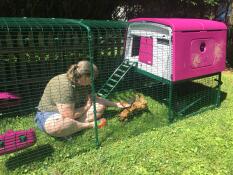 A girl sitting into an Omlet chicken coop