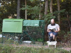 A man sitting and reading next to his chickens