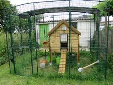 A large wooden chicken coop inside an Omlet chicken run.