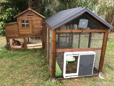 Grey automatic chicken coop door attached to wooden chicken coop