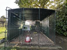 A large chicken walk in run set up in a garden.