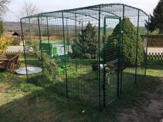 a large walk in run with a cube large green chicken coop attached