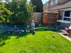 A child stood in front of green Zippi Tunnel connecting two rabbit runs in a garden.