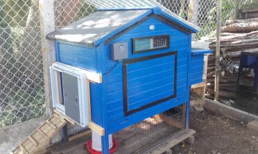 Omlet Grey Automatic Chicken Coop Door attached to Blue Wooden Chicken Coop