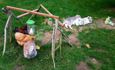 Chickens eating food while rabbits lay down in garden