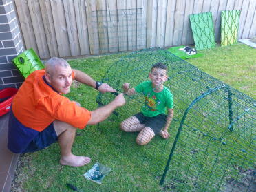 Man and child putting together their Omlet Eglu Go Rabbit Hutch Run