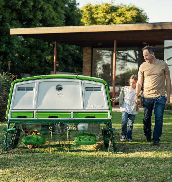 father and daughter walking beside the eglu pro chicken coop in the garden